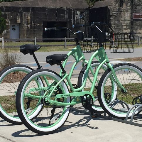 A row of mint green Tybee Island Bike Rentals cruisers parked by the old battery at Fort Screven