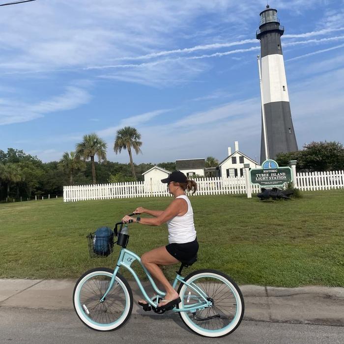 A rider on an aqua beach cruiser passing the Historic Tybee Island Light Station